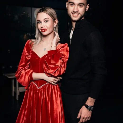 Пара в ярком красном платье и черной одежде на вечеринке в темном помещении