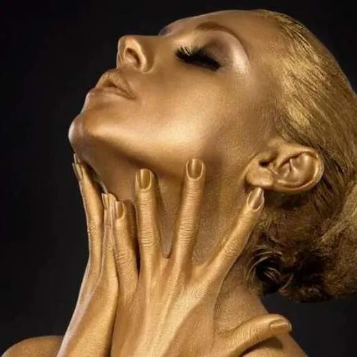 Женщина в золотом макияже позирует с поднятой головой на черном фоне в творческой студии