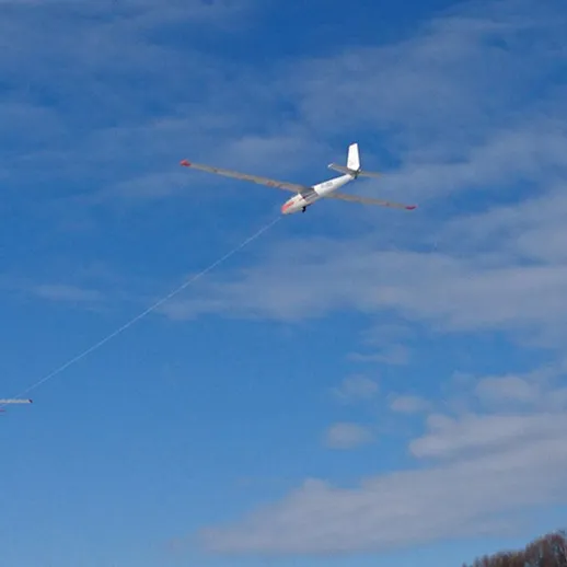 Беспилотник запускает малый самолет над облаками в ясный солнечный день