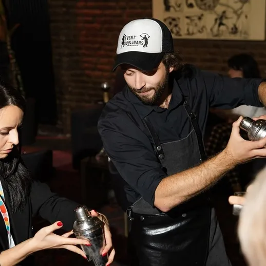 Участники мастер-класса по коктейлям готовят напитки в уютном баре вечером на мероприятии