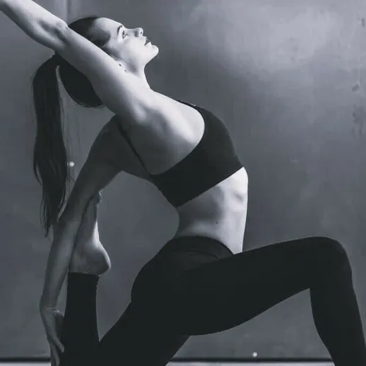 Йога-практика на фоне серой стены в зале, женщина выполняет асану, наслаждаясь моментом и сосредоточиваясь на дыхании