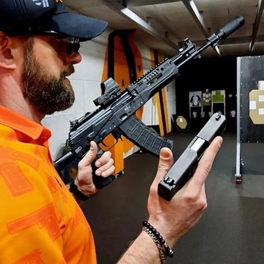 Стрельба с огнестрельным оружием в тире, мужчина с оружием в руках на тренировке в помещении