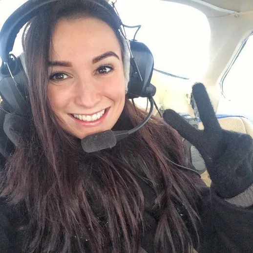 Девушка позирует с улыбкой в самолете во время полета на малой высоте в зимний день