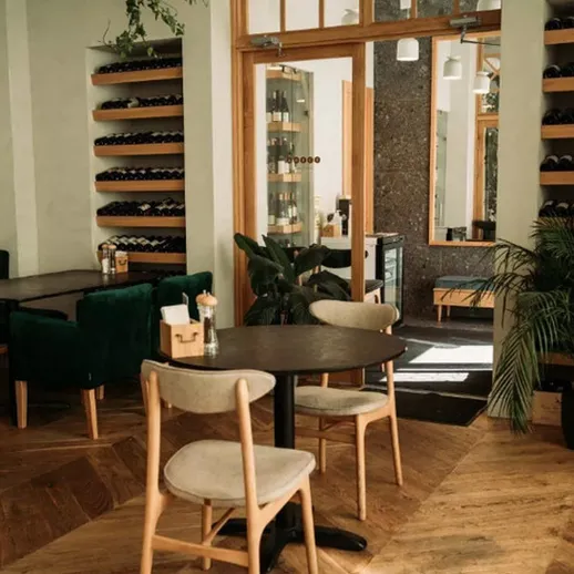 Уютный интерьер кафе с зелеными акцентами и деревянными деталями, расположенный в центре города в теплый день