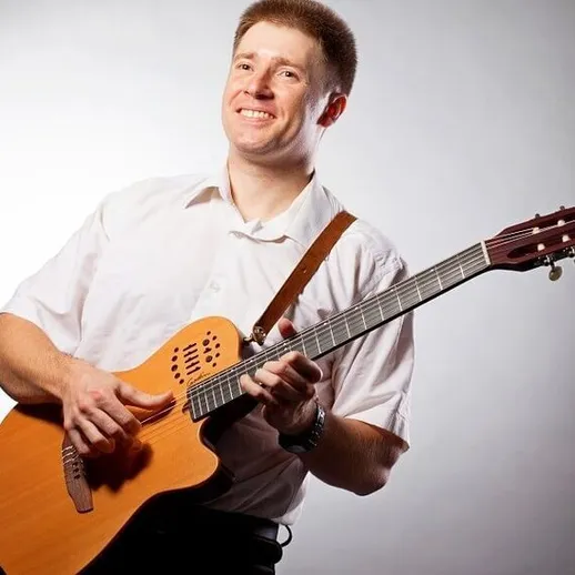 Музыкант играет на акустической гитаре в студии при мягком освещении