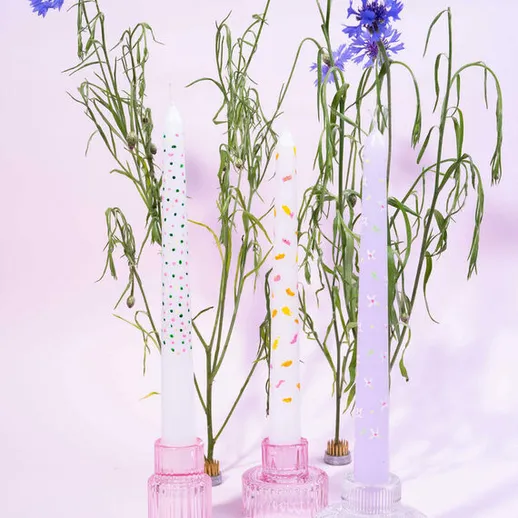 Красивые свечи и цветы в вазах на фоне нежного фона, создающие атмосферу уюта и спокойствия