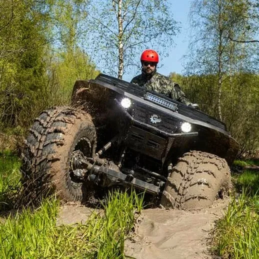 Внедорожник проехал через грязь в лесу в солнечный день, создавая брызги и следы на земле