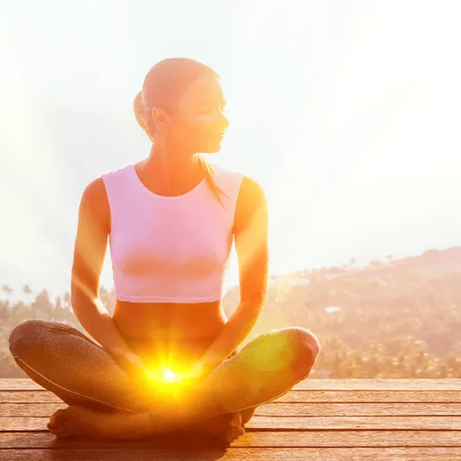 Медитация на солнце: девушка в белой футболке сидит на деревянной платформе среди природы в яркий день