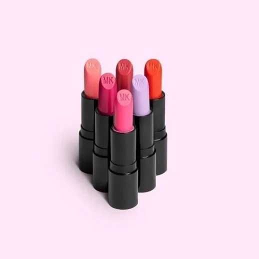 Коллекция помад на розовом фоне, различные цвета и оттенки помады, упаковка с логотипом