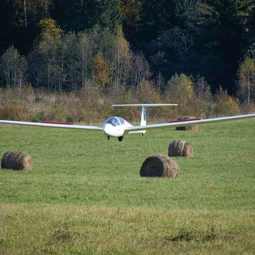 Параплан приземляется на зеленом поле с сеном в осенний день