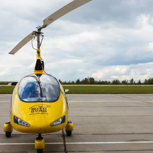 Желтый вертолет на аэродроме, готовый к взлету под облачным небом в ясный день