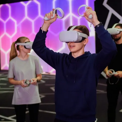 Группа людей пробует виртуальную реальность в игровой зоне с яркими фонами