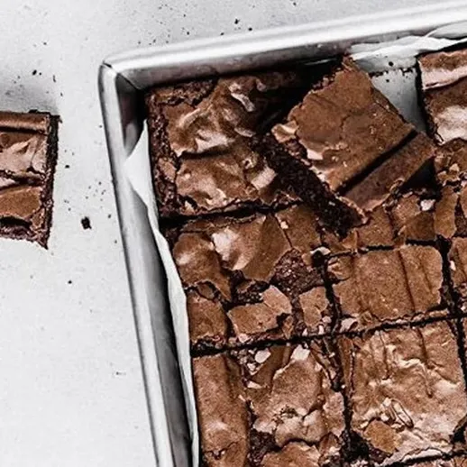 Вкусные коричневые брауни на белом фоне, нарезанные и готовые к подаче с кусочком рядом, домашняя выпечка