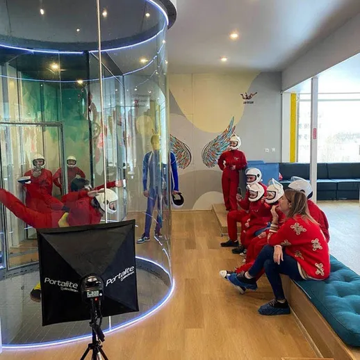 Группа людей в костюмах для полета в аэротрубке в центре активного отдыха