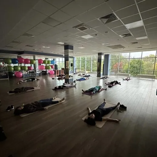 Групповая релаксация в студии йоги с участниками, отдыхающими на матах в солнечное утро