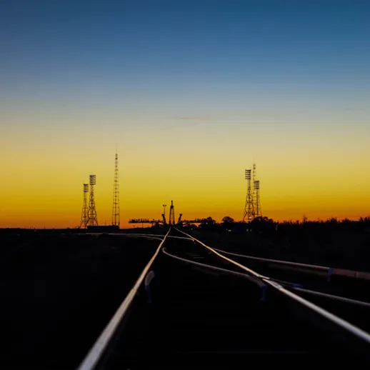 Вечерний пейзаж с железнодорожными путями и сигналами на фоне заката в открытой местности