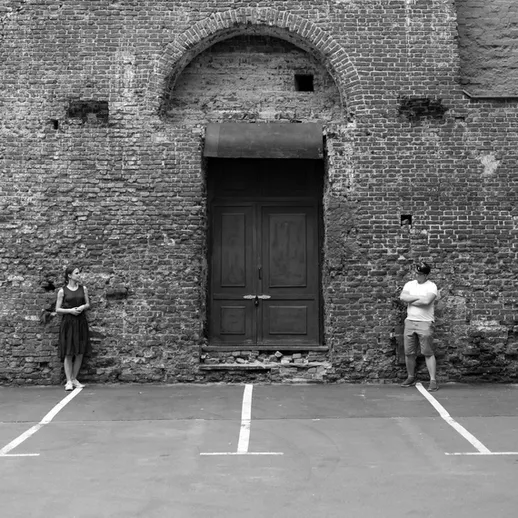 Пара людей рядом с кирпичной стеной в парковке старого здания