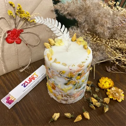 Уютная свеча из натурального воска с сухоцветами на деревянном столе