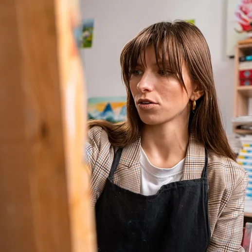 Художница работает над картиной в творческой студии, окруженной материалами и вдохновением