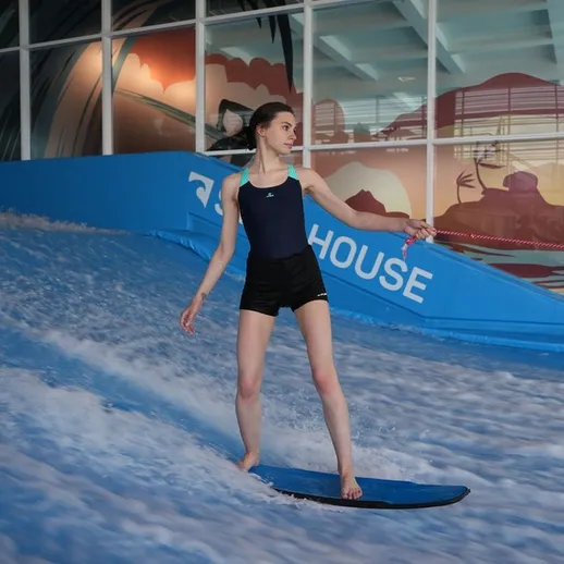 Серфинг на искусственной волне в развлекательном центре во время летних каникул