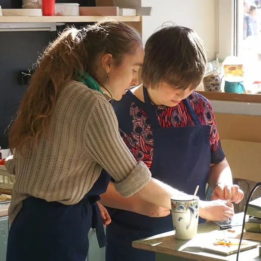 Два человека готовят еду на кухне, обучаясь кулинарным навыкам в светлом помещении в дневное время