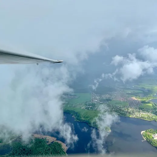 Облака и живописный ландшафт с высоты в полете над озерами и деревьями на фоне серого неба