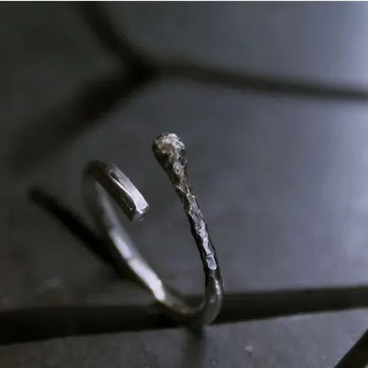 Изогнутый металлический предмет на черной поверхности при свете мягкого освещения