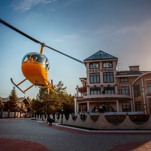 Вертолет летит над рестораном в живописном пейзаже под ясным небом в солнечный день