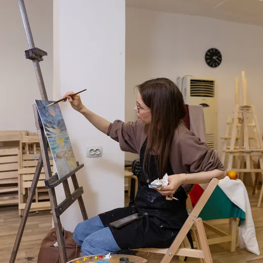 Художница создает картину в художественной студии во время мастер-класса