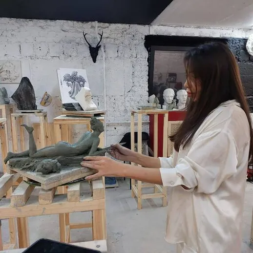 Художница работает над скульптурой в художественной мастерской в солнечное утро