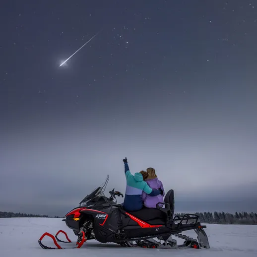Два человека на снегоходе смотрят на метеор в ночном небе над снежным полем