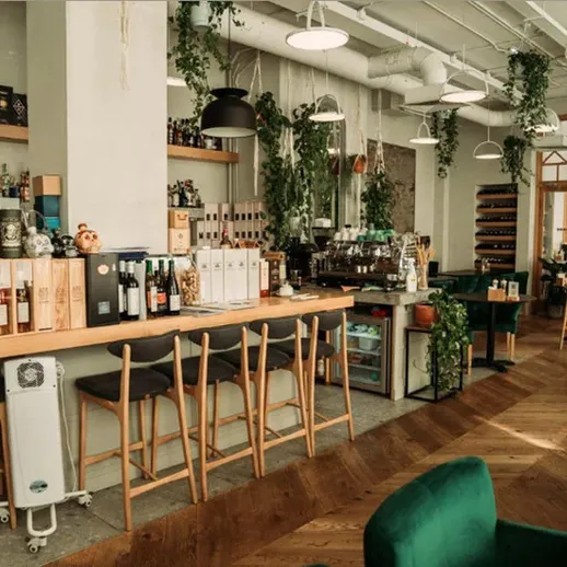Современный интерьер уютного кафе с барной стойкой и зелеными растениями, расположенного в центре города