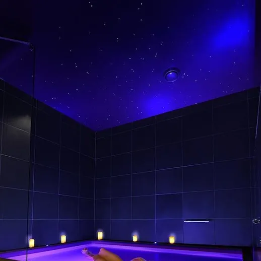 Женщина отдыхает в ванной с подсветкой и звёздным небом в вечернее время