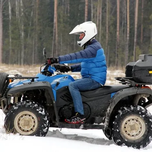 Мужчина на квадроцикле катается по snowy местности в зимнее время года в лесу