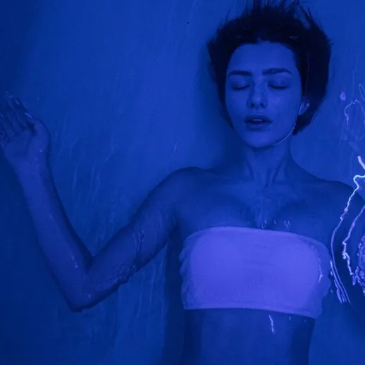 Женщина плавает в воде с синими огнями вокруг в спокойной обстановке