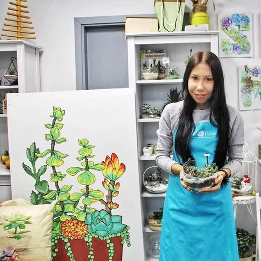 Молодая женщина с цветочным горшком стоит в цветочном магазине, окруженная растениями и декоративными элементами