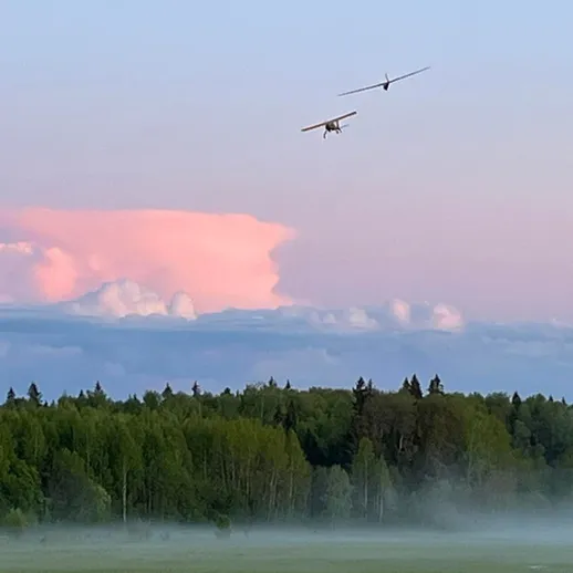 Два самолета пролетели над лесом на фоне вечернего неба с облаками в спокойной атмосфере при закате