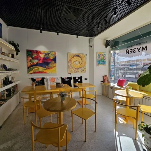 Яркое кафе с желтой мебелью и современными картинами на стенах в день