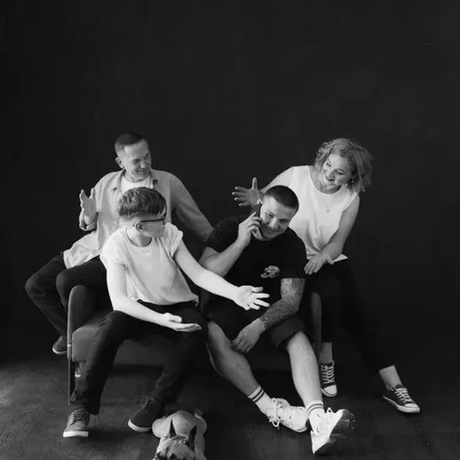 Группа людей на диване во время весёлого общения с собакой в тёмной комнате