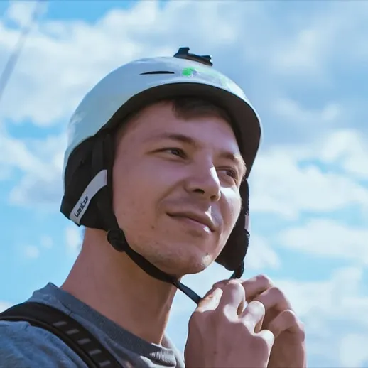 Молодой человек надет шлем, готовится к активному отдыху на свежем воздухе под ясным небом