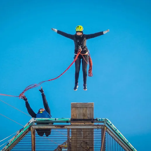 Экстремальный прыжок с высоты с платформы в ясный день на фоне синего неба