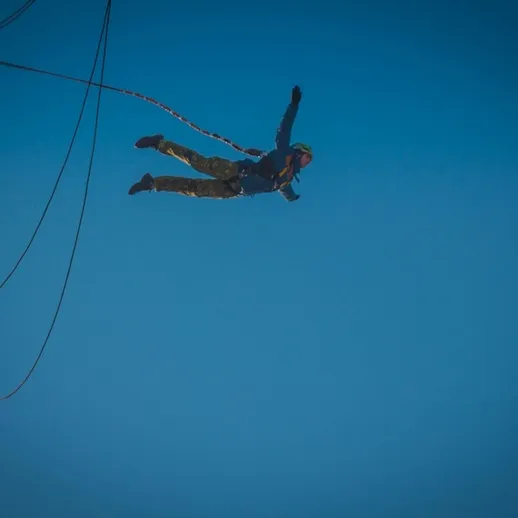 Стремительное падение человека с высоты во время занятия банджи-джампингом в ясный день