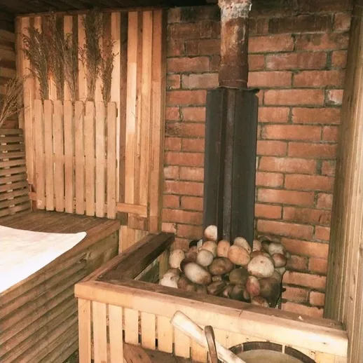 Уютная баня с кирпичной печью и камнями, расположенная в загородном доме на вечере, готова к посещению