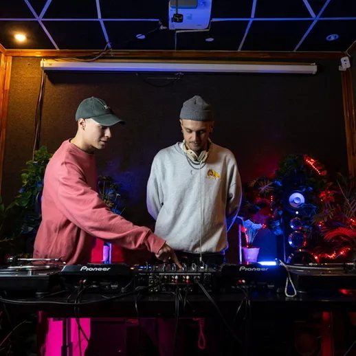 Два ди-джея за пультами в клубе, которые создают атмосферу вечеринки в ночное время