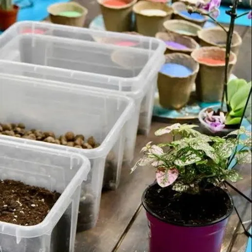 Участники мастер-класса по садоводству работают с растениями и материалами на столе в светлом помещении