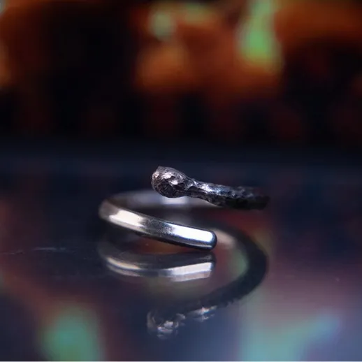 Изогнутое кольцо из серебра на блестящей поверхности с теплым фоном