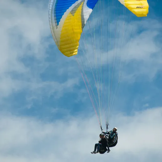 Парапланеристы в небесах над живописным ландшафтом под ярким солнечным светом