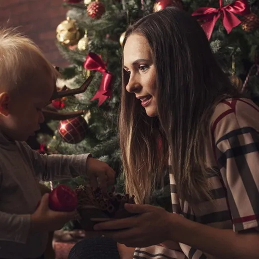 Рождественское утро с маленьким ребенком, который играет с подарками рядом с елкой в уютном доме