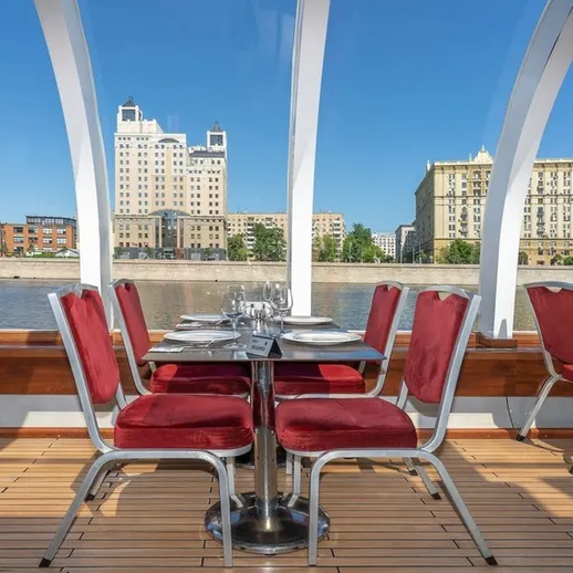 Обеденная зона на речном теплоходе с панорамными окнами и видом на Москву в солнечный день