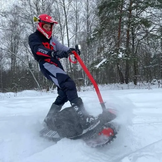 Молодой человек катается на снегомобиле на снегу в лесу зимой